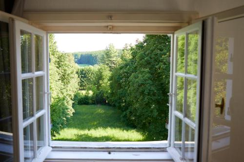an open window with a view of a garden at Schloss Mörlbach in Icking