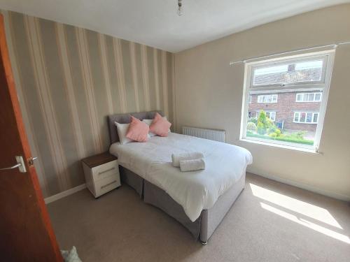 a bedroom with a bed with pink pillows and a window at Newcastle Park House in Stoke on Trent