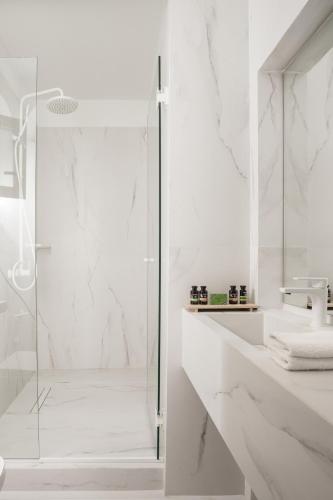 a white bathroom with a shower and a sink at SYROS SOUL LUXURY SUITES in Ermoupoli