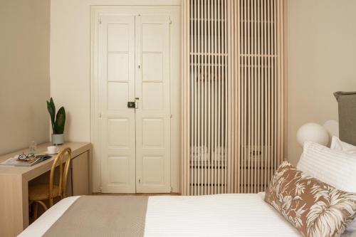 a bedroom with a bed and a desk and a door at SYROS SOUL LUXURY SUITES in Ermoupoli