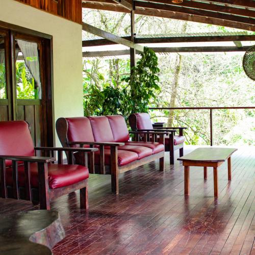 a porch with couches and a table and a tableearcher at Princesa de la Luna Ecolodge in Fortuna