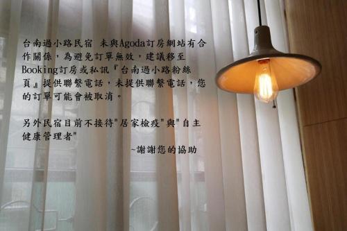 a lamp and a curtain with writing on a window at Through A Path in Tainan