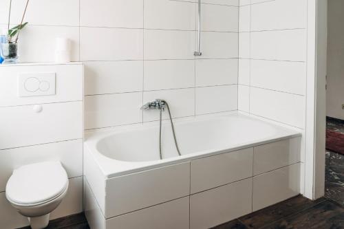 a white bathroom with a tub and a toilet at Fördeblick in Flensburg