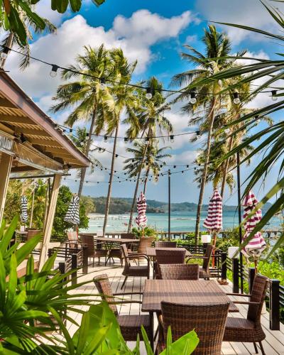 a patio with tables and chairs and palm trees at Shantaa Resort, Kohkood in Ko Kood