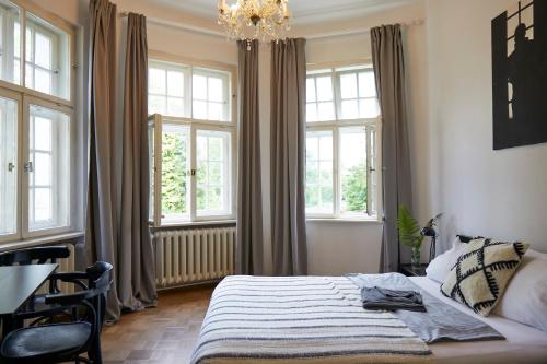 a bedroom with a bed with a chandelier and windows at Schloss Mörlbach in Icking