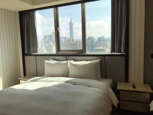 a bedroom with a large white bed with a large window at Hej Taipei Arena Hotel in Taipei