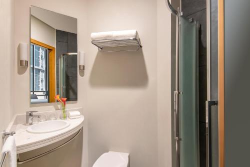 een witte badkamer met een wastafel en een douche bij ibis Doha in Doha