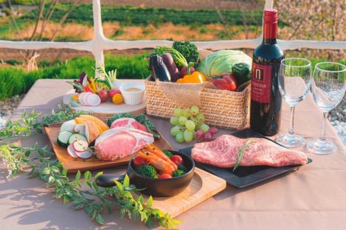 a table with plates of food and a bottle of wine at Blissful Garden - Vacation STAY 46392v in Shibukawa