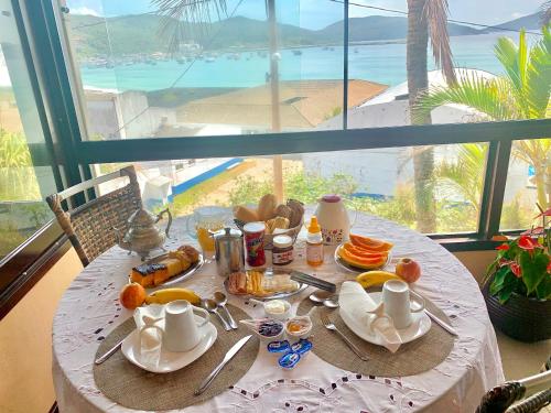una mesa con desayuno y vistas al océano en Guesthouse Saint Tropez, en Arraial do Cabo