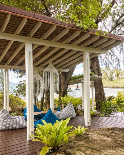 a wooden pergola with blue chairs on a deck at Shantaa Resort, Kohkood in Ko Kood