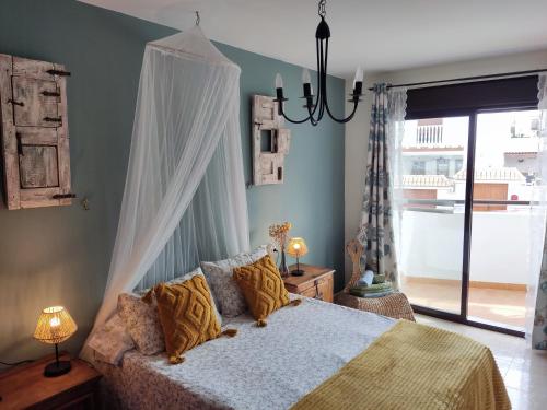 a bedroom with a bed and a chandelier at LA PITA- Terraza con vistas al mar & parking, a 1 min de la playa in Carboneras