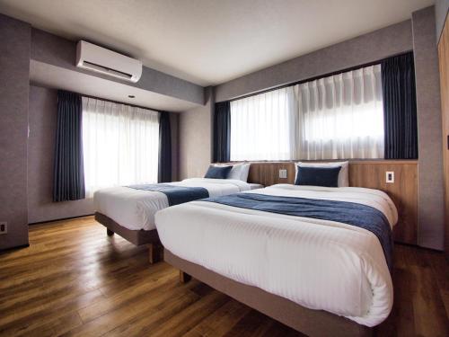 2 camas en una habitación de hotel con ventanas en ulu Tokyo en Tokio