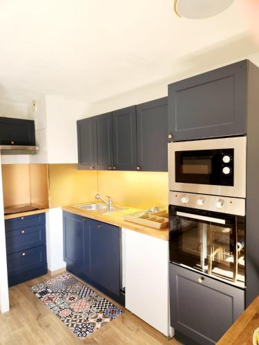 - une cuisine avec des placards bleus et blancs et une cuisinière dans l'établissement Appartement cosy 4 personnes charme estival à la montagne, à Les Deux Alpes