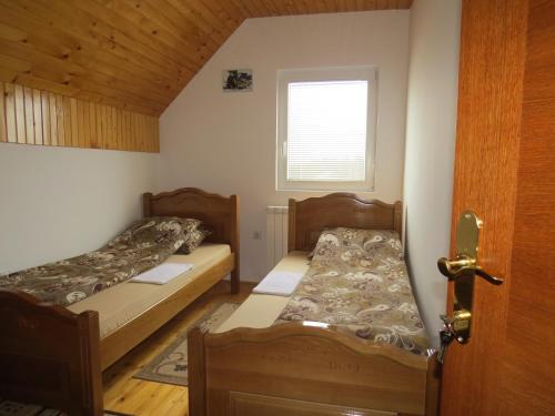 two beds in a small room with a window at Rooms and Bungalows Sreten Žugić in Žabljak