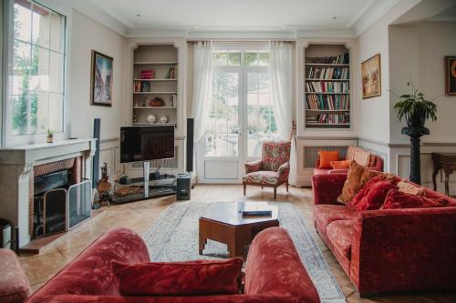 a living room with red couches and a fireplace at Chateau la Tilleraie in Bergerac