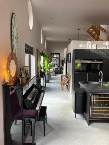 a living room with a piano and a kitchen at Koetshuis aan het water 3 bedroom villa in Voorburg