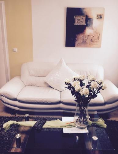 a living room with a couch and a table with flowers at Wilsmann Apartmentvermietung in Hövelhof