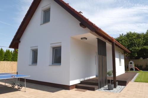 a white house with a ping pong table in front of it at Bell Nyaraló Agárd in Gárdony