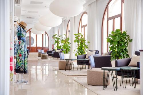 a woman in a dress standing in a lobby with tables and chairs at Hotel Esplendido in Port de Soller