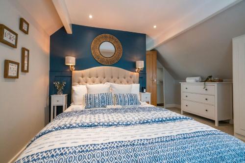 a bedroom with a large bed with a blue wall at Pilgrim Cottage in Tarvin