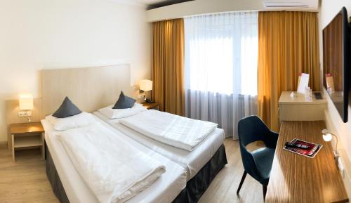 a hotel room with a large bed and a chair at City Hotel Ost am Kö in Augsburg