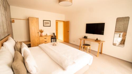 a bedroom with a white bed and a television at Boutique Hotel Soyka in Špindlerův Mlýn