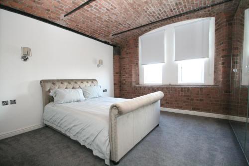 a brick bedroom with a bed and a window at Waterloo warehouse in Liverpool