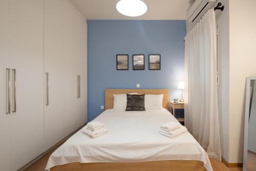 a bedroom with a white bed with a blue wall at Exclusive apartment in the heart of Athens in Athens