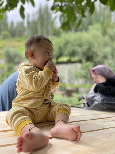 a baby sitting on a table eating a piece of food at Karakorum View Hotel Karimabad Hunza in Hunza