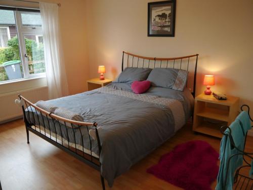 a bedroom with a bed with two lamps and a window at Arakhova in Kirkcudbright