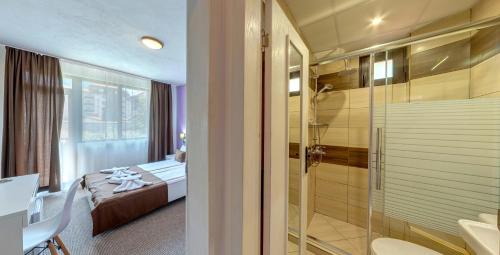Grami Hotel في بانسكو: حمام مع دش وغرفة نوم مع سرير