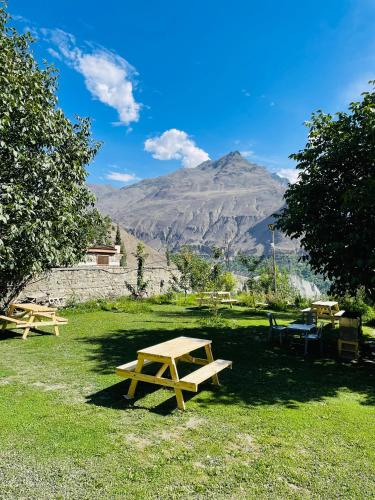 two picnic tables in a field with a mountain in the background at Karakorum View Hotel Karimabad Hunza in Hunza