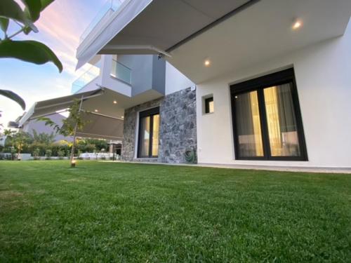 a house with a green lawn in front of it at Olea Suites 1 in Nea Moudania