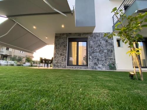 a house with a green lawn in front of a building at Olea Suites 1 in Nea Moudania