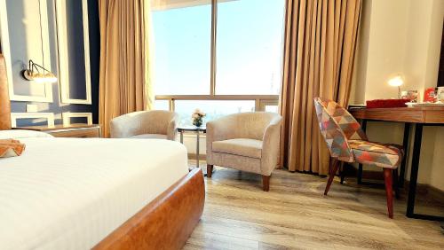 a hotel room with a bed and a desk and chairs at Best Western Premier Hotel Gulberg Lahore in Lahore