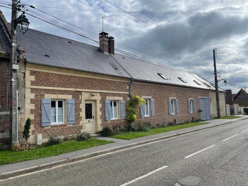 a brick building with blue windows on a street at Confortable duplex au cœur de la campagne Picarde à 1h de Paris in Biermont