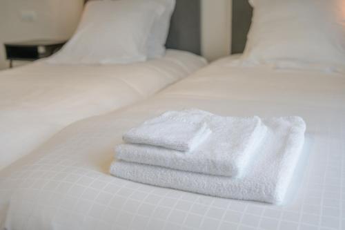 two white towels are stacked on a white bed at De Vesten Comfort Lodge in Laakdal