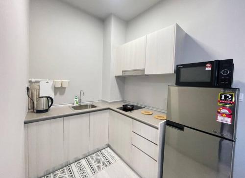 a small kitchen with a refrigerator and a microwave at Jesselton Quay,2BR,4-5pax,Mountain view in Kota Kinabalu