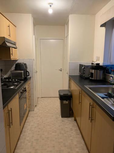 eine Küche mit einem Waschbecken und eine Tür in ein Zimmer in der Unterkunft 39 Abbey Court Coventry in Whitley