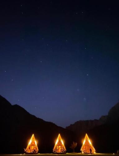 a group of three tents lit up at night at Etno apartmani Komarnica in Šavnik