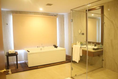 La salle de bains est pourvue d'une baignoire, d'un lavabo et d'une douche. dans l'établissement Trivik Hotels & Resorts, Chikmagalur, à Chikmagalur