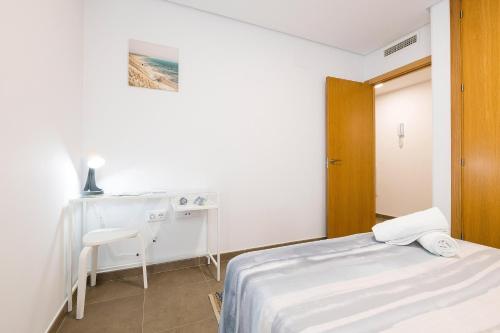 a small bedroom with a bed and a desk at Jardines Iro in Chiclana de la Frontera
