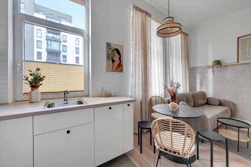 a kitchen and living room with a table and a couch at Downtown Apartments Chmielna Park - City Center & Parking in Gdańsk