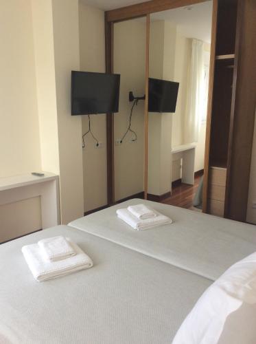a bedroom with a bed with two towels on it at Posada H.El Alba in Boó de Piélagos