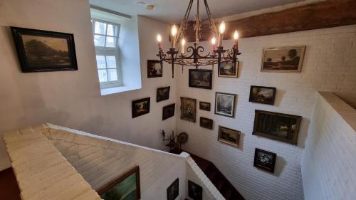 a staircase with pictures on the wall and a chandelier at Landgoed Kasteel Terborgh in Schinnen