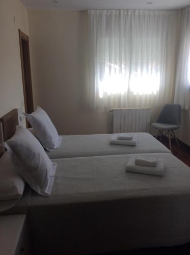a bedroom with two beds with white pillows and a window at Posada H.El Alba in Boó de Piélagos