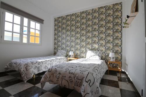 a bedroom with two beds and a patterned wall at Aloha***Burrero cerca del Aeropuerto in Playa del Burrero