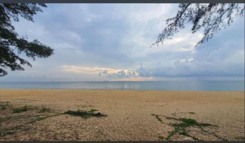 a beach with a cloudy sky and the ocean at Paka Tamim Seaview Hotel in Paka