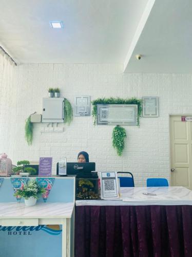 a person sitting at a desk with a laptop at Paka Tamim Seaview Hotel in Paka