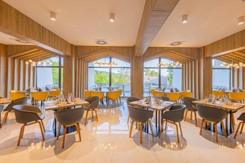 um restaurante com mesas, cadeiras e janelas em Avar Hotel em Matrafured